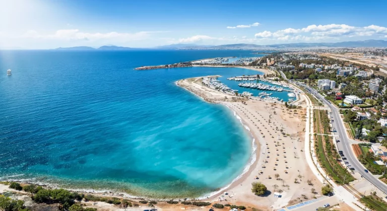 Вид с воздуха на популярное побережье Глифада, южный пригород Афин, Греция, с пляжами, причалами для яхт и бирюзовым морем