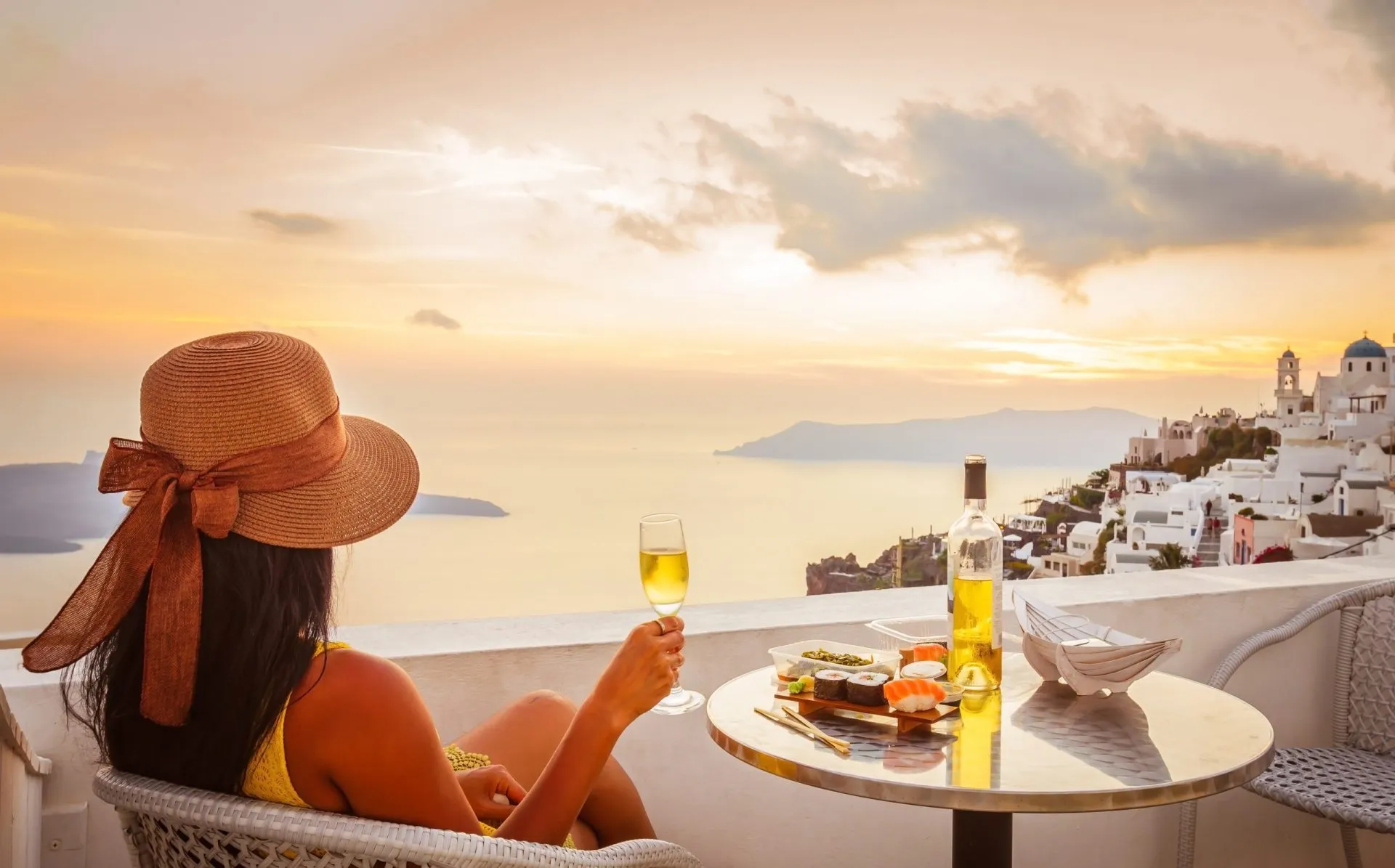 Female tourist enjoying food, wine and sunset view at Santorini, Greece