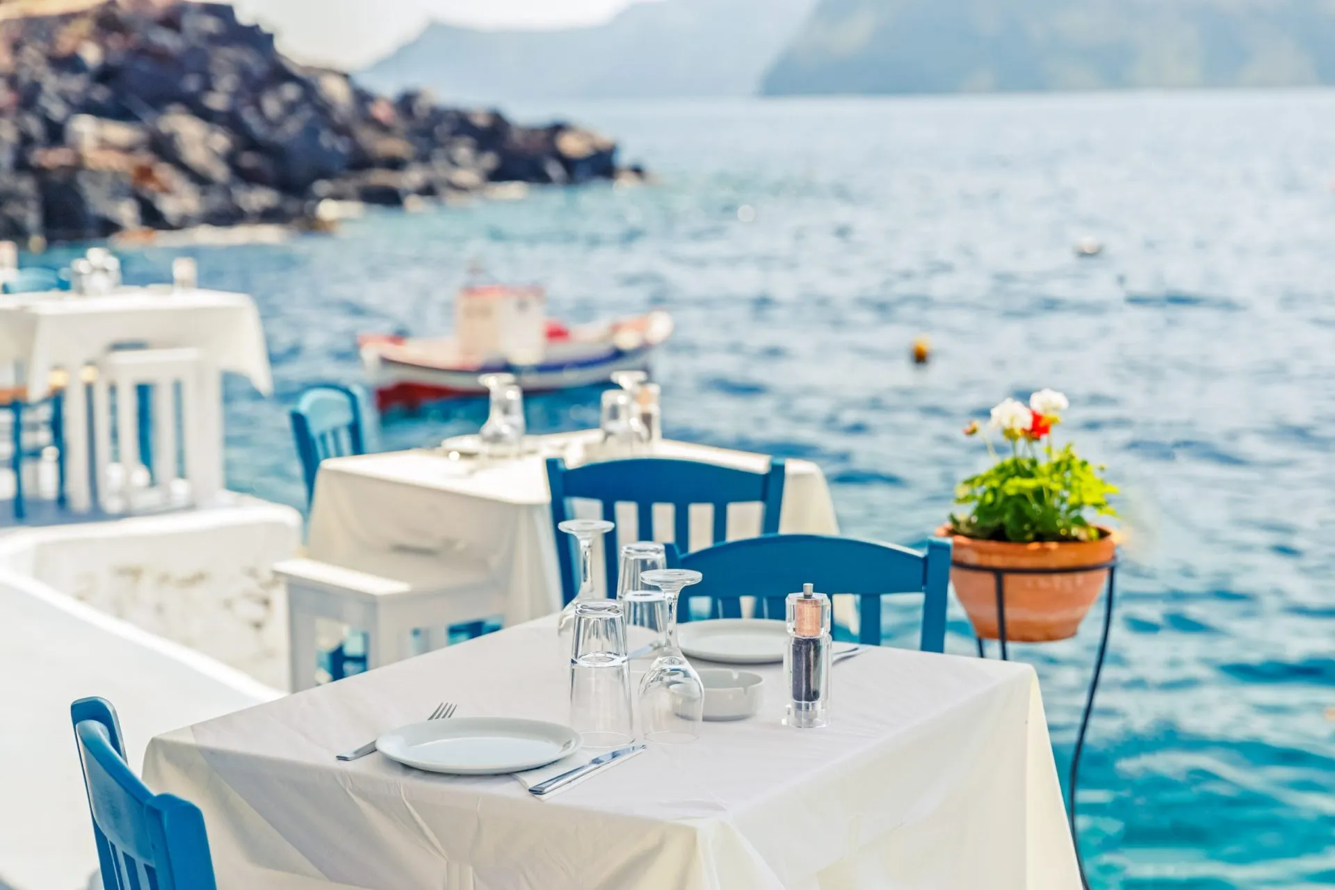 Greece, Santorini. Restaurant with served table in seafront of Aegean sea on Santorini Cyclades island with breathtaking, amazing and unbelievable view on the water and embankment of Oia Ia village.