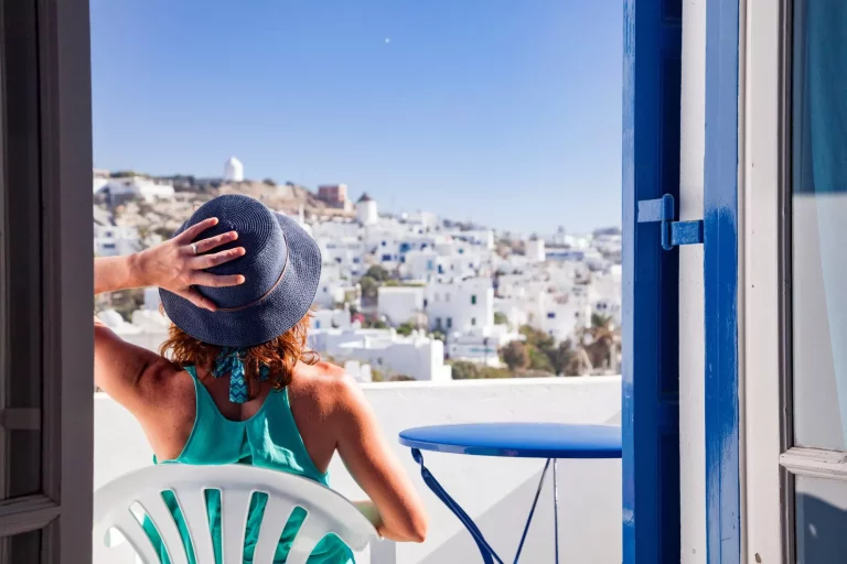 kvinna njuter av utsikten över Mykonos stad från terrassen, Grekland - sommarsemester