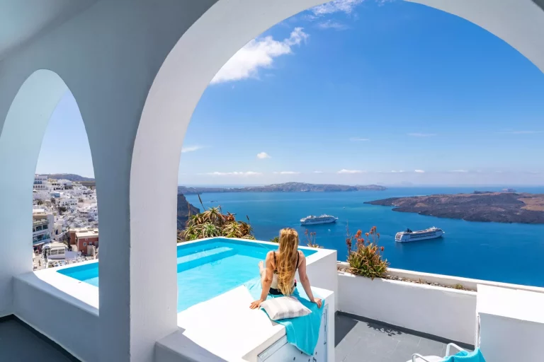 Fond de vacances d'été de luxe. Jeune femme en vacances à Santorini, femmes à la piscine regardant l'océan Caldera de Santorini, fille à la piscine à débordement Santorini Grèce